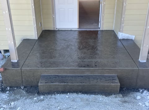 Concrete front porch and steps at residential entrance with white double doors and support columns