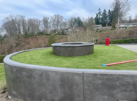 Spiral concrete pathway with green lawn and central circular structure in a residential landscape setting