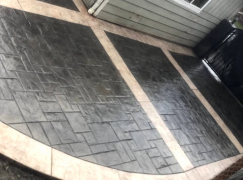 Curved patio with dark herringbone tile pattern and stone border
