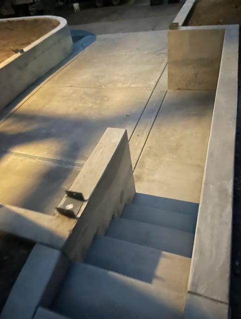 Empty concrete industrial containers or troughs with metal dividers, photographed from above in sunlight