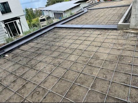 Overhead view of flat roof with concrete tiles and metal safety grille grid pattern installation